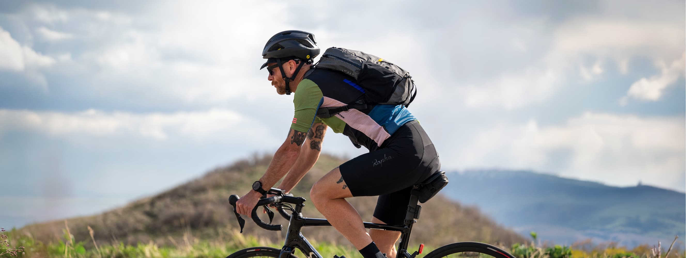 Cyclist riding with a lightweight minimalist backpack on a scenic mountain road outdoors