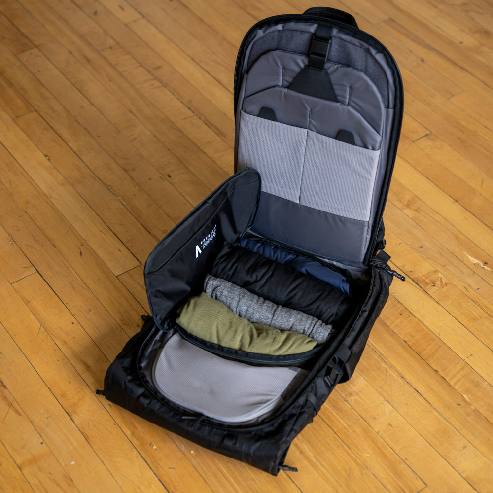 Open backpack on a wooden floor with clothes inside